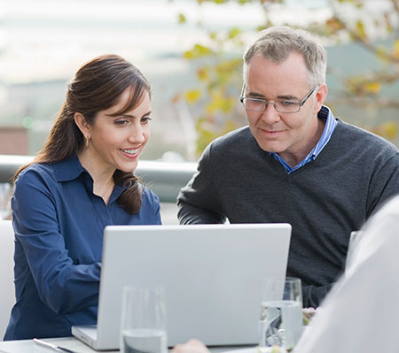 A woman and a man reading news articles on a laptop