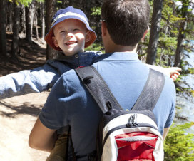 Man carrying a backpack and child while hiking