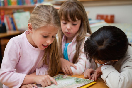 group of kids reading a book in class