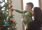 mom and kid putting bulbs on christmas tree