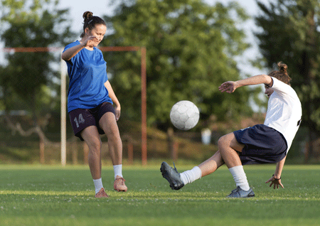 girls playing soccer on a field