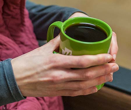 Hands holding green mug with coffee