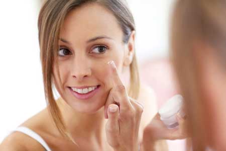 woman applying moisturizer to dry skin