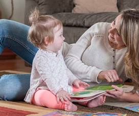 Mom reading book with infant daughter
