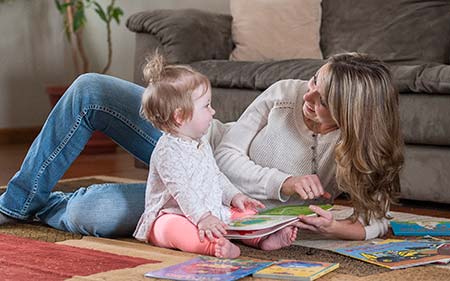 Mom reading book with infant daughter