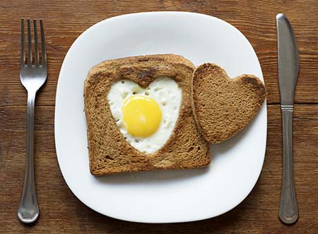 Egg cooked in toast's heart-shaped hole on plate