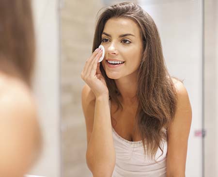 Woman looking in a mirror, cleaning her face