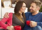 Couple talking on couch drinking coffee