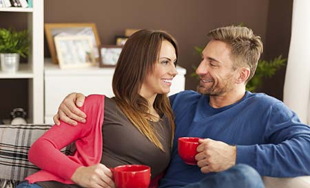 Couple talking on couch drinking coffee