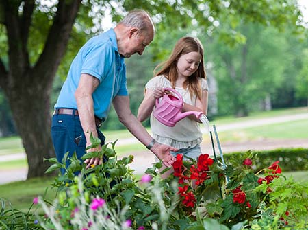Girl watering flowers with Grandpa