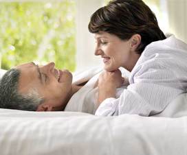 couple smiling in bed, woman has short hair