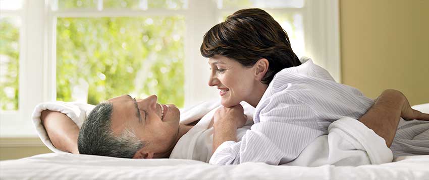 middle-aged couple smiling in bed