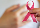 woman holding pink ribbon with hand on breast