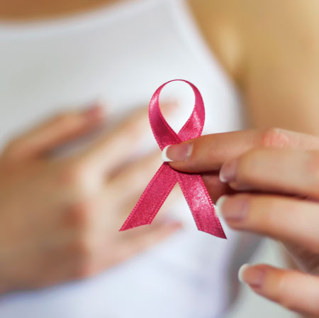 close up of woman holding pink ribbon, hand on breast