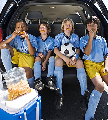 Kids in the back of van eating orange slices