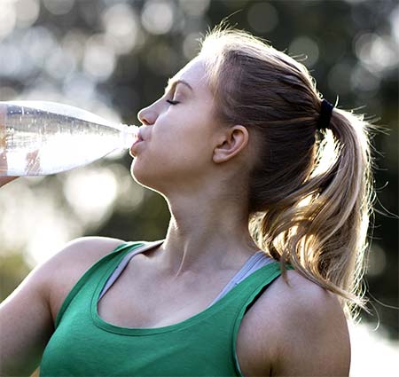 Pretty teenager drinking water after working out