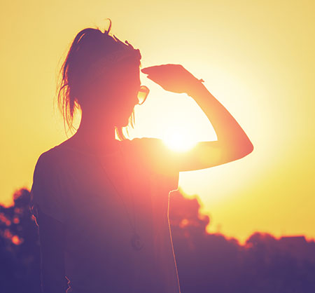 A woman protecting her eyes from the sun, thinking about whether she has a sun allergy.