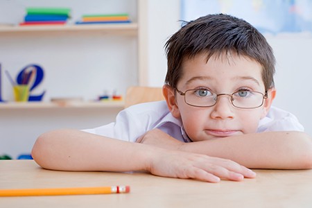 boy with glasses at his desk at school