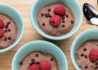 Four dishes of chocolate chia pudding topped with raspberries and chocolate pieces