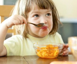 Young girl eating carrots at the kitchen table