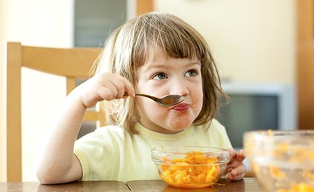 Young girl eating carrots at the kitchen table