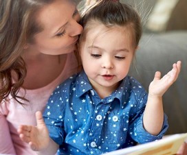 Mom kissing daughter on forehead during story time