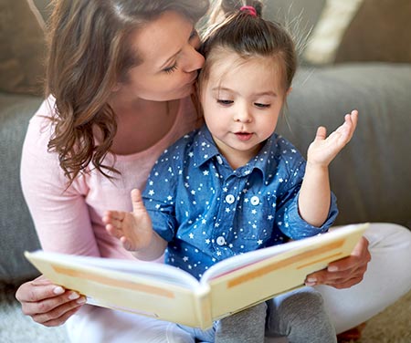 Mom kissing daughter on forehead during story time