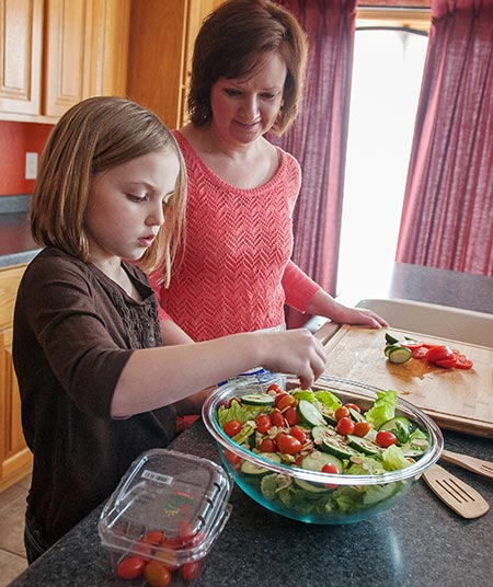 Mom and daughter prepping healthy salad - dietary guidelines