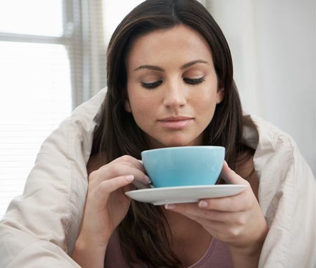 Woman wrapped in a blanket drinking tea
