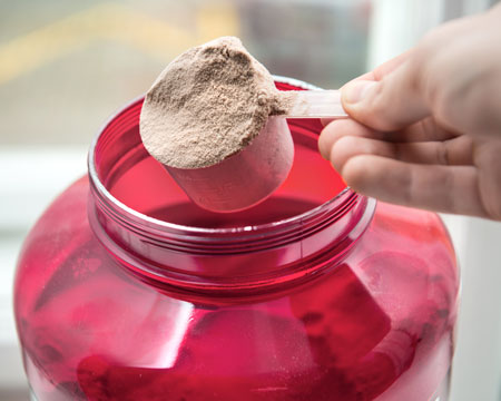 person scooping protein powder shake