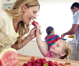 Young girl feeding her mom a strawberry
