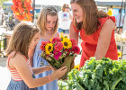 Mom with daughters smelling flowers at farmers market