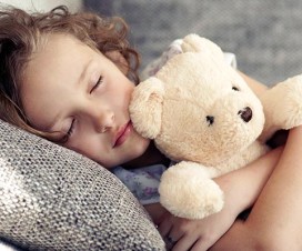 Young girl napping on sofa holding teddy bear - Do your kids need a nap?