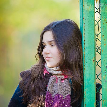 Teenage girl leaning against a fence - Adolescent health and heart disease