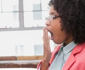 Woman yawning at her desk: Why am I yawning so much and what I can do about it?