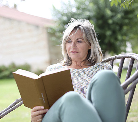 Woman sitting outside, reading a book - cancer basics
