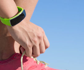 Woman wearing an activity tracker, tying her shoe - Fitness trackers: Are they worth it?