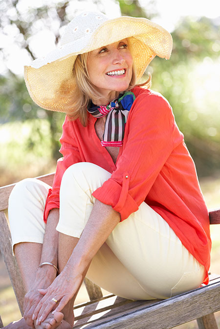 Woman with large sun hat sitting outside - Concerns about sun exposure after cancer