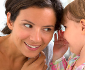 girl whispering in mom's ear