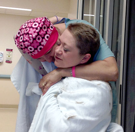 Friends embrace after one shaves her head to show support of friends cancer treatment