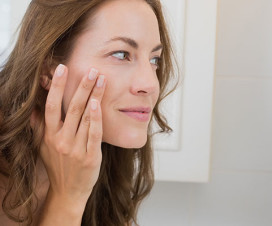 Woman looking closely at her face in the mirror - What's aging your face?