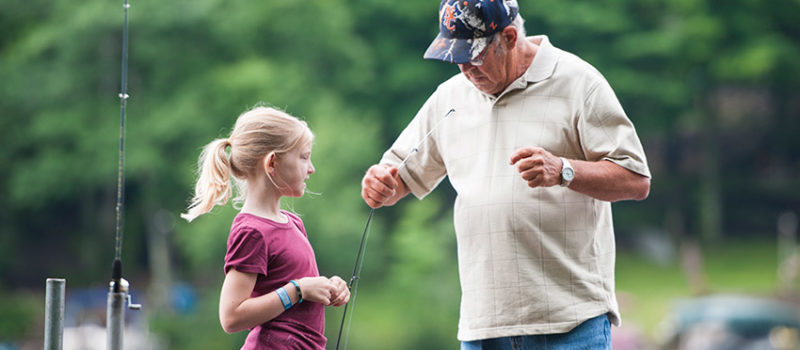 Grandpa setting up fishing pole for granddaughter - Fishing Safety
