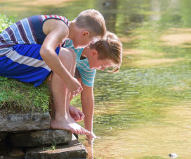 Two boys playing on a river bank - River and stream safety