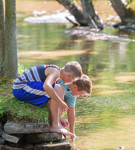 Two boys playing on a river bank - River and stream safety