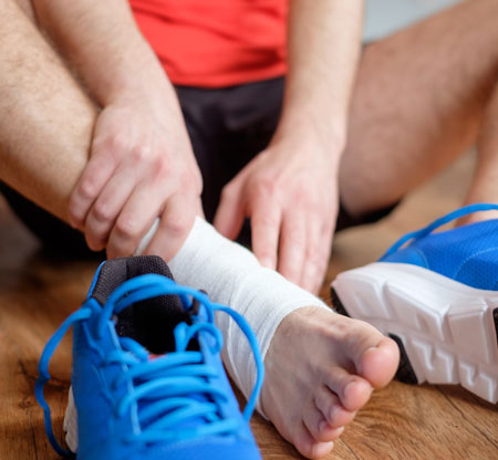 Man holding his foot with ankle tape getting ready to workout