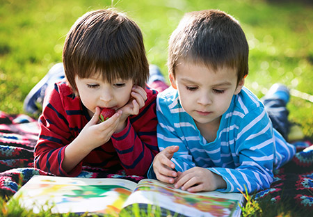 Two boys reading outside on a summer day - Keeping up school skills during the summer