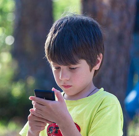 Young boy playing games on a mobile phone - Video gaming benefits