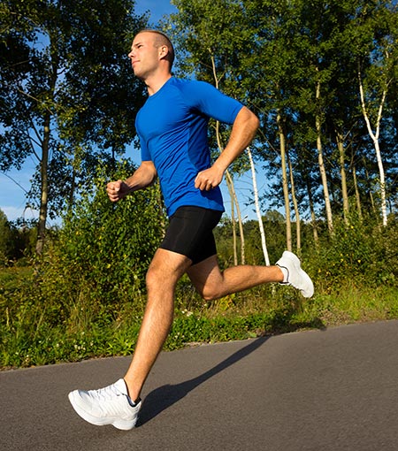 Man jogging outside on trail – Can exercise reduce cancer risk?