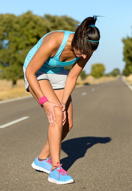 Woman experiencing keen pain while running on pavement - Knee pain causes and fixes