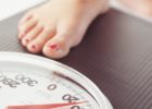 Woman stepping on a scale - How often should you weigh yourself?